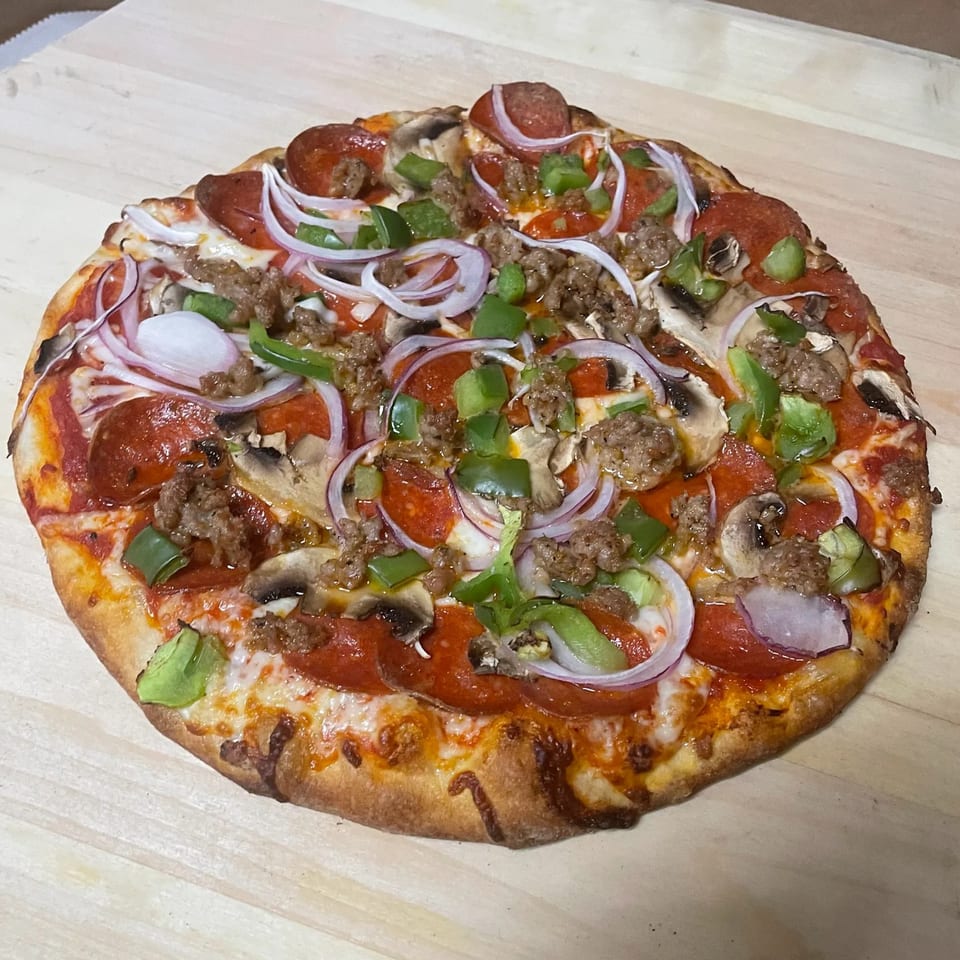 A TopCrust Jupiter Kitchen pizza with pepperoni, sausage, mushrooms, green peppers, and red onions.